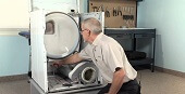 Специалист проверятет тепловой насос сушильной машины для диагностики.